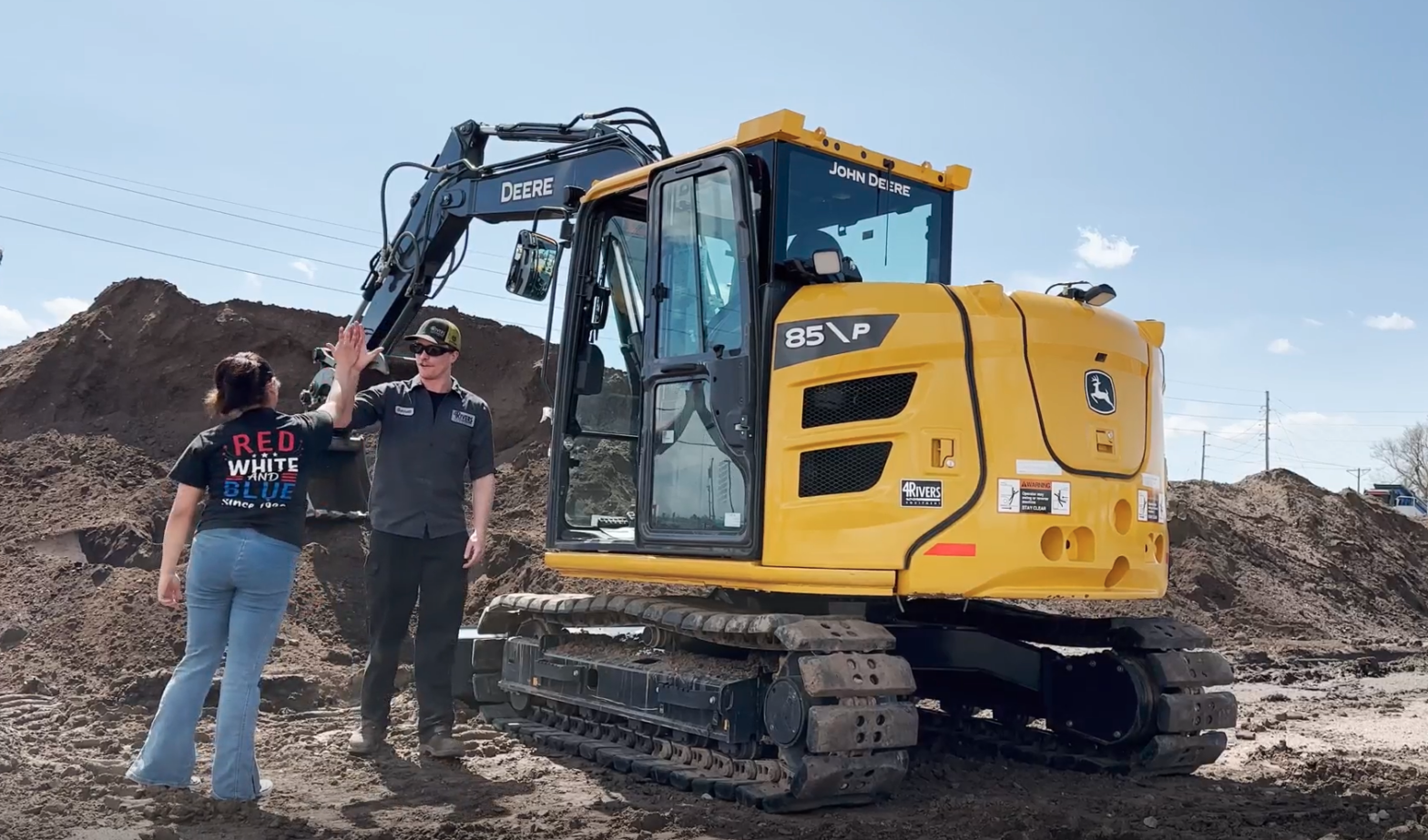 Gaby Yanez and a 4Rivers technician high five beside an excavator.